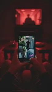 Person playing a game on smartphone, TV background