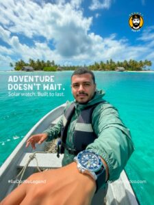 Man on boat with ocean and island backdrop, wearing watch.