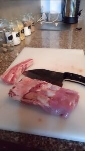 Raw lamb meat on chopping board with cleaver.