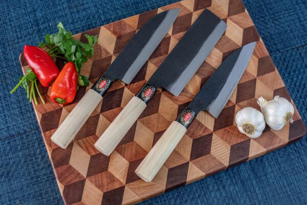 Japanese knives on wooden board with peppers, garlic.