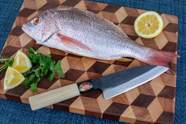 Whole fish with knife and lemon on board.