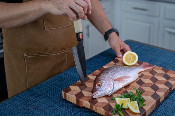Person preparing fish with lemon on cutting board.