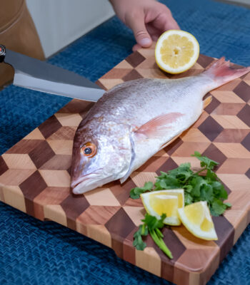 Preparing fish with lemon and herbs on cutting board.