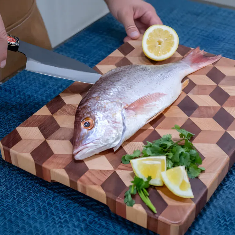 Preparing fish with lemon and herbs on cutting board.