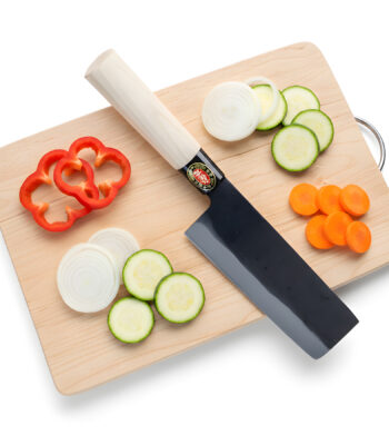 Knife with sliced vegetables on cutting board