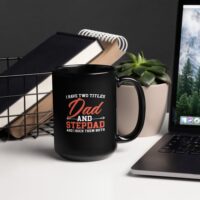 Black mug with 'Dad and Stepdad' text on desk.