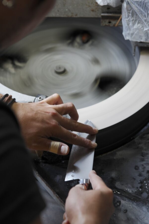 Sharpening knife on spinning wheel with hands.