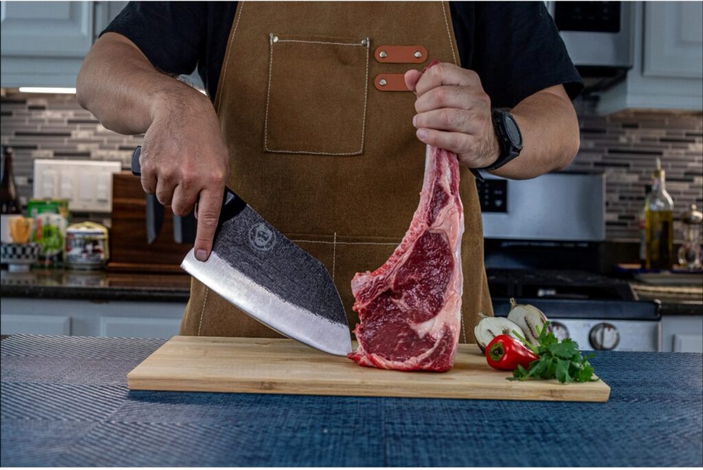 Person cutting raw steak in kitchen.