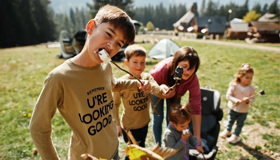 Family enjoying roasted marshmallows at campsite.