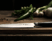 Chef's knife on cutting board with vegetables