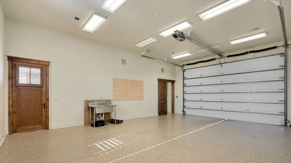 Spacious empty garage with sink and automatic door.