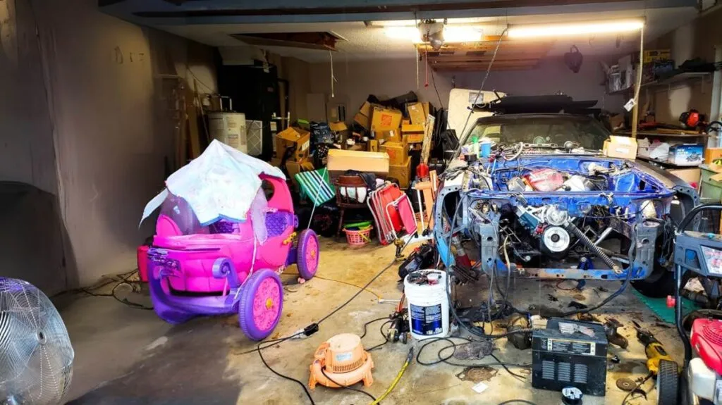 Cluttered garage with tools, car parts, and toys.