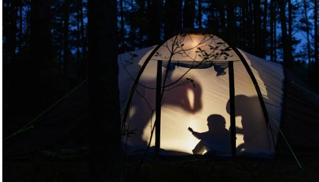 Silhouettes inside tent camping at night.