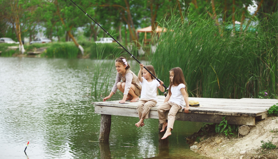 Children fishing on lakeside dock.