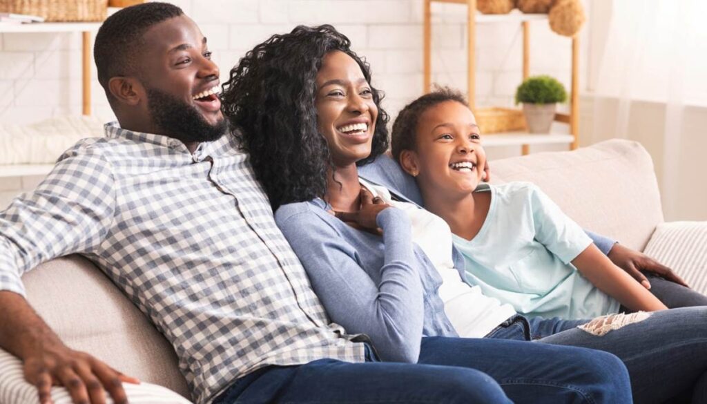 Happy family laughing on couch together.