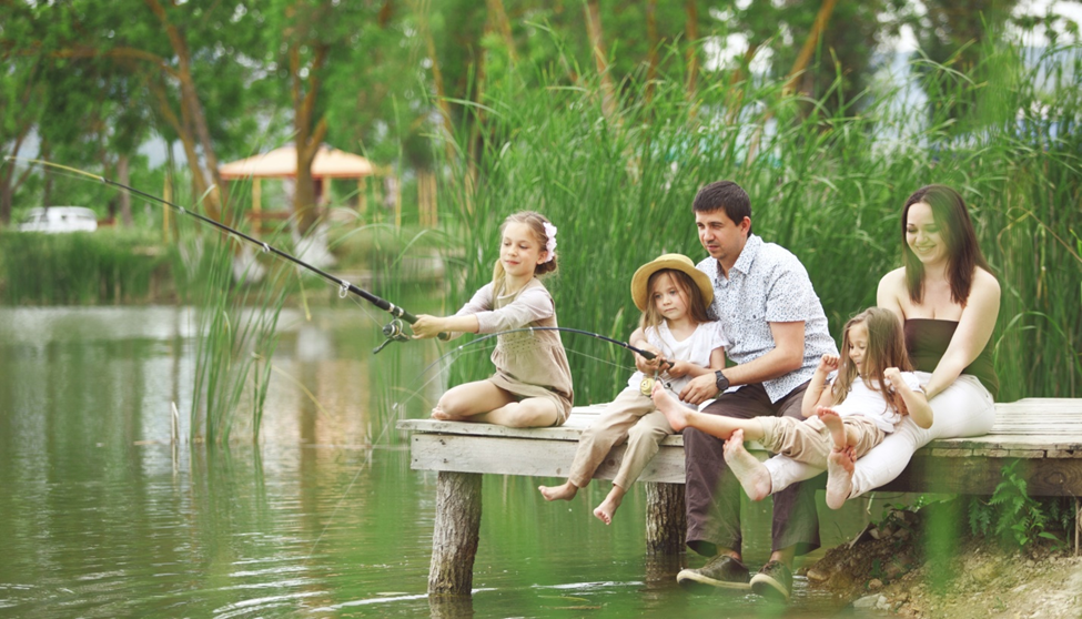 Family fishing on a lakeside dock, enjoying nature.