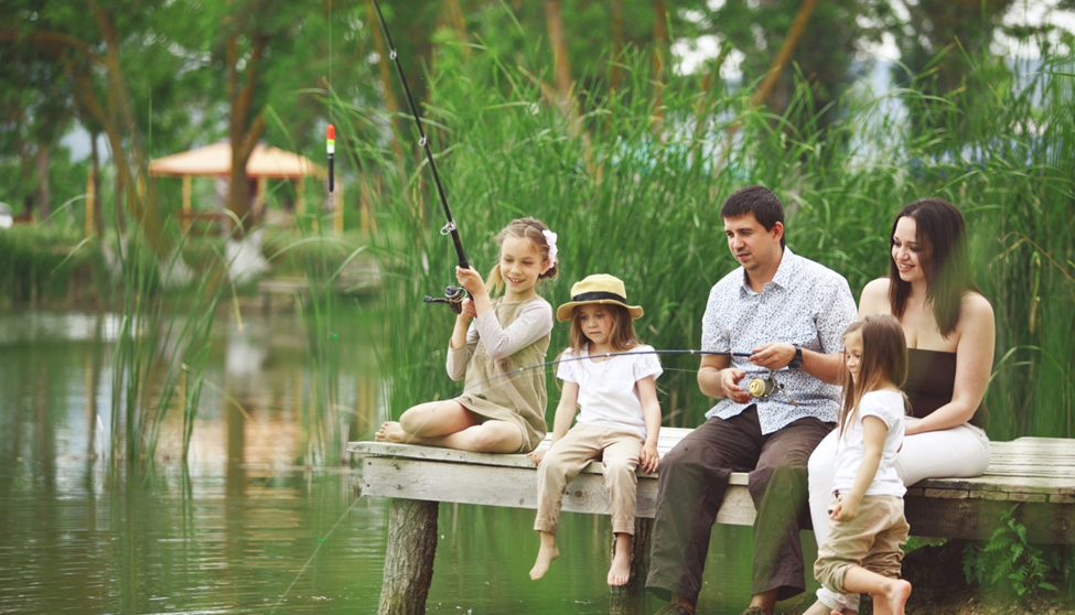 Family fishing together on a wooden dock.