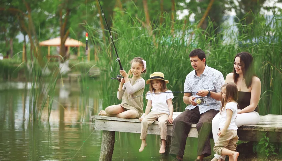 Family fishing together on a wooden dock.