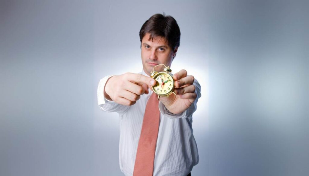 Man holding gold clock, pointing at time.