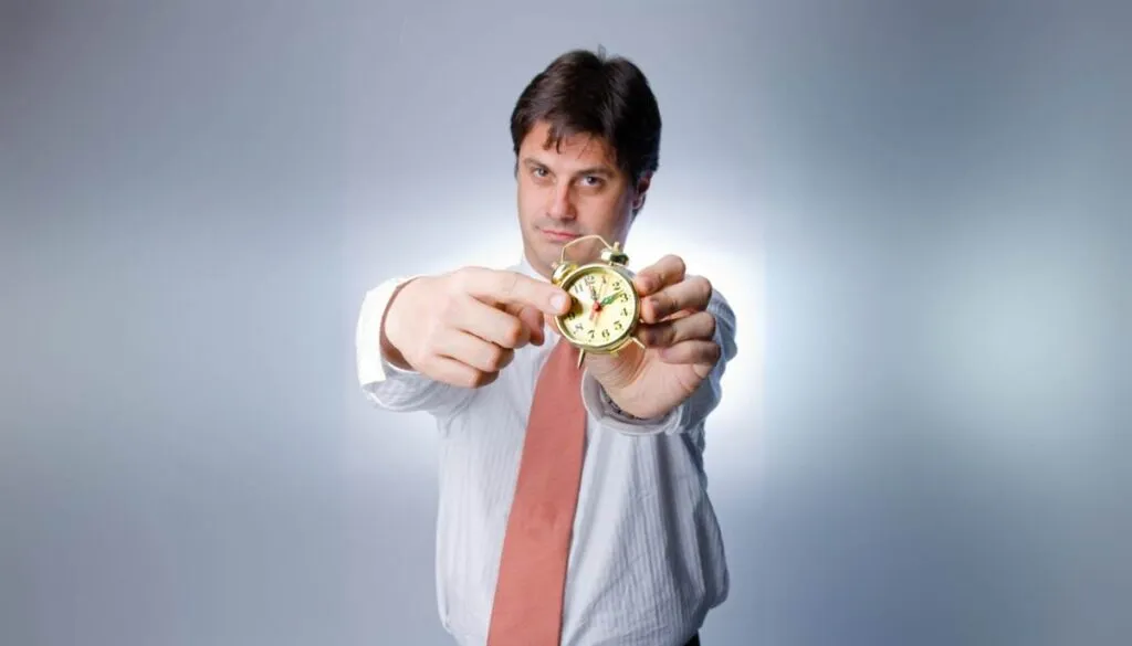 Man holding gold clock, pointing at time.