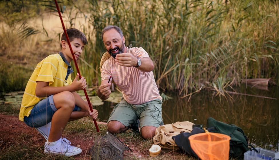 Father and son fishing by a pond.