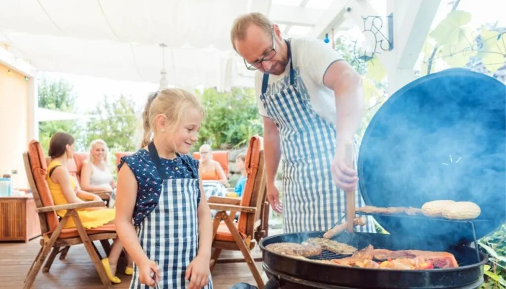 Father and daughter grilling at outdoor family barbecue.