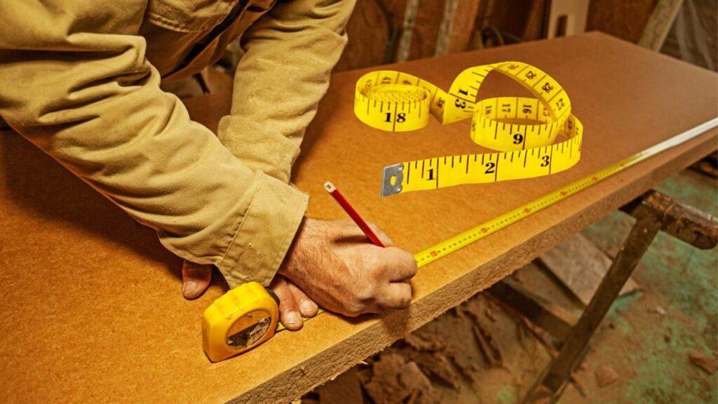 Carpenter measuring wood with tape measure and pencil.