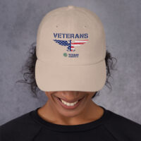 Smiling person wearing a veterans cap.