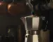 Bialetti Moka pot on a gas stove with espresso emerging into the upper chamber in morning light