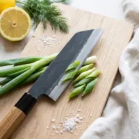Aogami Bunka Keyaki knife with lemon and dill on a pale oak board