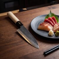 Japanese chef knife beside sashimi on plate