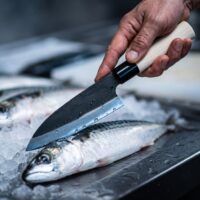 Chef slicing fresh fish on ice bed