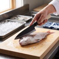 Chef slicing whole fish on wooden board